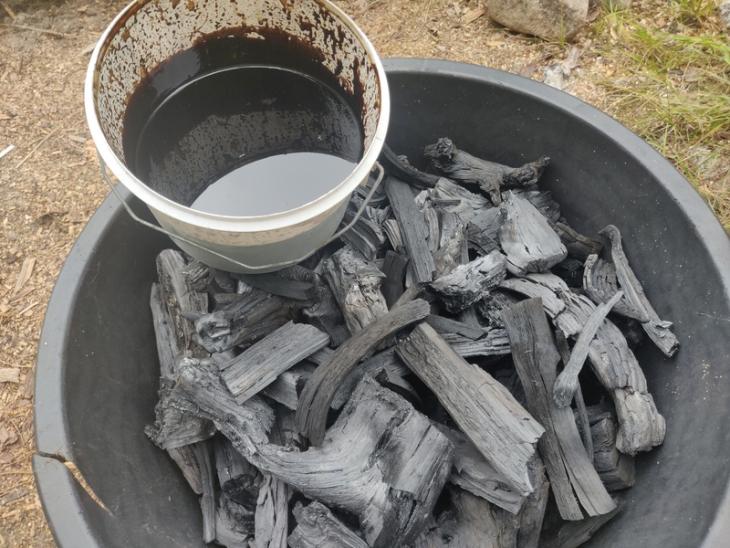 A small bucket of tar, a big bucket of charcoal.